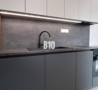 A kitchen unit in a 2-room apartment with a black sink and a built-in oven.