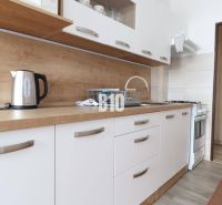 A bright kitchen with white cabinets and a wooden decor countertop in a 3-room apartment.