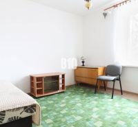Interior of a 3-room apartment with carpeted flooring, an armchair, and a lamp by the window.