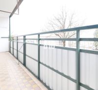 Balcony of a 3-room apartment with a view of trees and paving.