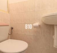 Toilet and sink in the bathroom of a 3-room apartment with tiles.
