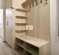 A hallway in a 3-room apartment with a wooden decor floor, a wall mirror, and coat hooks.