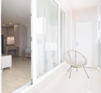 A balcony with a view into a studio apartment, wooden decor flooring, cozy seating.