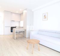 Living room in a one-bedroom apartment with a wooden decor floor and light furniture.
