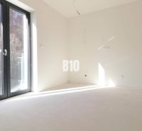 An empty room in a 3-room apartment with large windows and a view of nature.