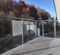 A balcony of a 2-room apartment in Dolný Kubín with glass railing and surrounded by trees.
