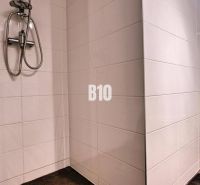 Bathroom in a 3-room apartment with white tiles, a shower, and a toilet.