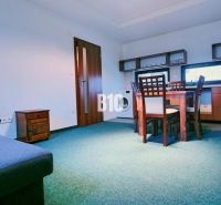 Living room with a sofa, dining table, and kitchenette in a three-room apartment.