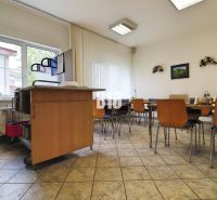 A dining area in a production facility with wooden chairs and a sink.