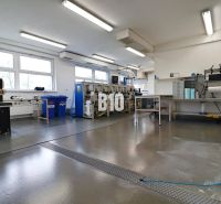 Manufacturing spaces with industrial machines and workbenches, clean and spacious interior.