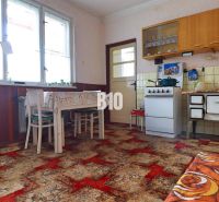 A kitchen in a family house with retro furniture, tiles, and a bold carpet.