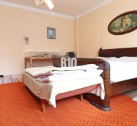 The interior of a family house with two beds, wooden furniture, and an orange carpet.
