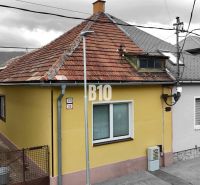 A family house in Martin with a yellow facade and a sloped roof, next to the access walkway.