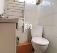 Bathroom in a family house with white tiles, a sink, and a toilet.