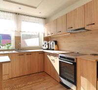 A kitchen in a family house with a wooden decor floor and furniture in light shades.