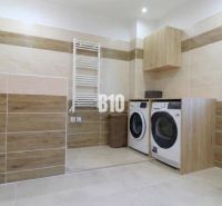 Laundry room in a family house with a washing machine, dryer, and a wooden decor floor.