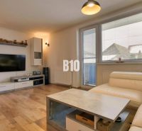 Living room in a 3-room apartment with a wooden decor floor and a comfortable white sofa.
