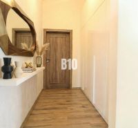 Narrow hallway in a family house with a wooden decor floor and a decorative mirror.