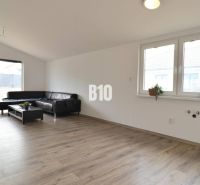 Living room in a family house, light sofa, wooden decor flooring, large windows.