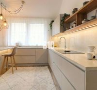 A kitchen in a family house with bar stools, interesting lights, and a wooden decor floor.
