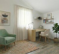 A study in a family house with an armchair, a desk, and a floor with a wooden decor.