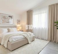 A bright bedroom with a large bed, curtains, and plants in a family house.