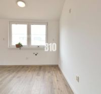 An empty room in a family house with a wood-patterned floor and a window.