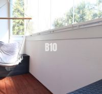 A glazed balcony in a 2-room apartment with a wooden decor floor and a hammock.