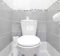 A bathroom in a 2-room apartment with a toilet, tiled with gray tiles.