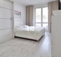 A bright bedroom with a large bed, wardrobe, and wooden decor flooring in a 2-room apartment.