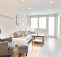 Living room with a sofa, armchair, and wooden decor flooring in a 3-room apartment.
