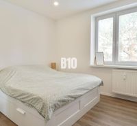 A bedroom in a 3-room apartment with a bed, a desk, and a floor with a wooden decor.