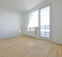 An empty room with a wood-patterned floor, a large window, and white walls.
