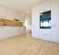 A kitchen in a 3-room apartment with white cabinets and a wood-patterned floor.