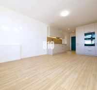 A kitchen in a 3-room apartment with a wood-patterned floor, white furniture, and appliances.
