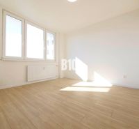 A room in a 3-room apartment with large windows and a floor with a wooden decor.