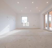 A spacious room with white walls and large windows, awaiting completion in a family house.