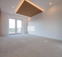 The interior of a family house with large windows and incomplete floor covering.