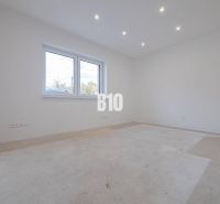 Empty room in a family house, white walls, large window, ceiling lighting.