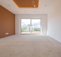 Living room of a family house with a brown wall and a large window without flooring.
