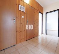 A hallway in a 3-room apartment with tiles, wooden paneling, and entrances to other rooms.