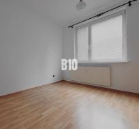 An empty room with walls in a 3-room apartment, a floor with a wooden decor, a large window.