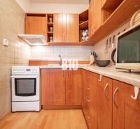 A kitchen in a 2-room apartment with wooden decor flooring and cabinets.