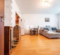 Living room in a two-room apartment with a wooden decor floor, a sofa, and a dining table.