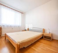 Bedroom in a 2-room apartment with a bed and a wooden decor floor.