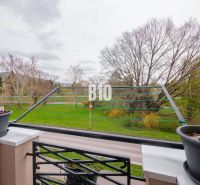 Balcony of a 3-room apartment in Nitra with a view of greenery and a row of trees.