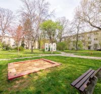 Courtyard in Nitra with a children's sandbox, benches, and surrounding residential buildings.