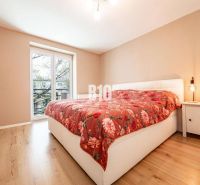 A bedroom in a 3-room apartment with a wooden decor floor and orange bedding.