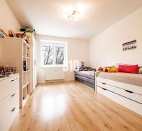 Children's room in a 3-room apartment with a bed, shelves, and a wooden decor floor.