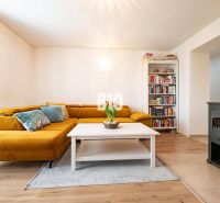 Living room in a 3-room apartment with a mustard sofa, a bookshelf, and a tiled stove.